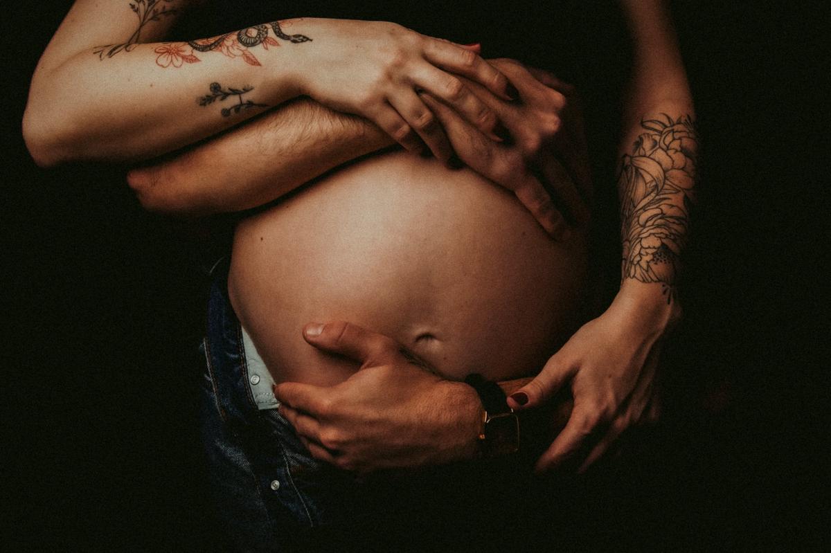 Les mains d’un couple posées sur un ventre de grossesse