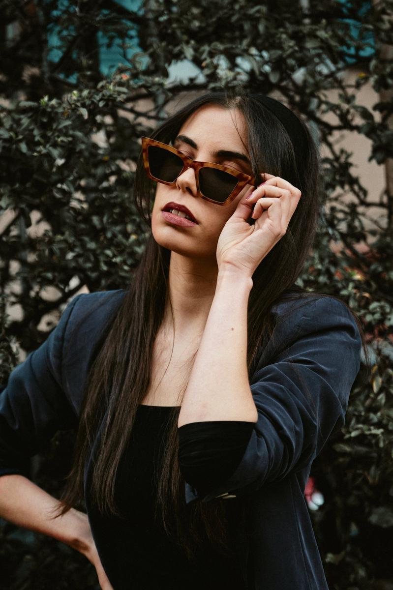Portrait d’une femme portant des lunettes de soleil devant un feuillage